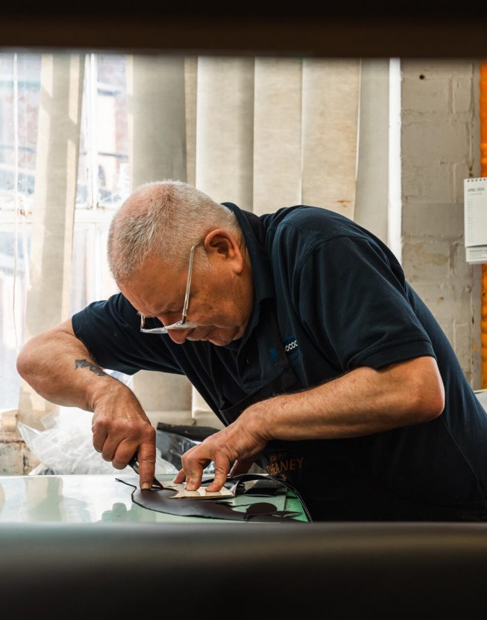 Skilled Cheaney shoemaker cutting out leather